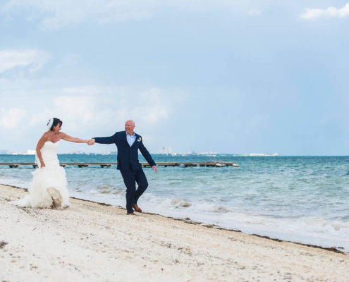 groom and bride walking along beach after wedding.