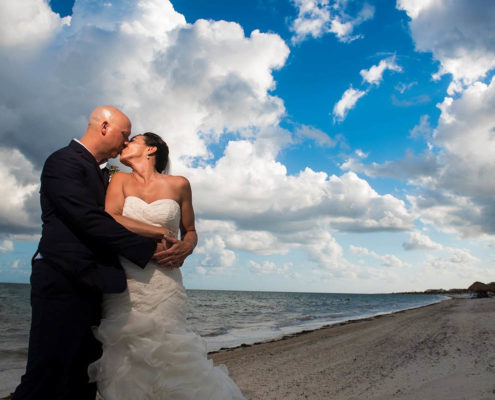 bride and groom kiss on the beach