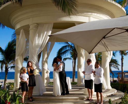 wedding ceremony with seaside behind bride and groom as they say their vows.