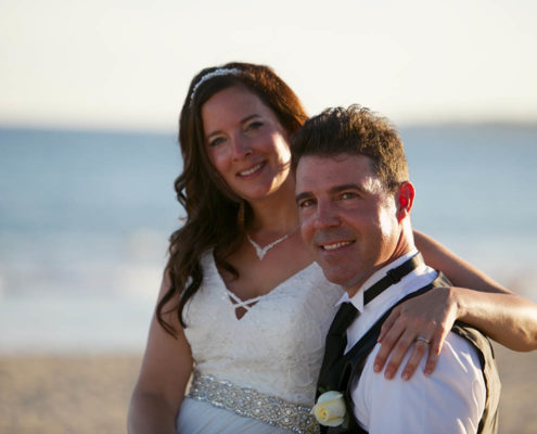 bride and groom pose for beach wedding photo