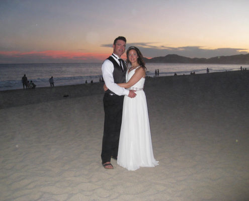 bride and groom pose on beach at sunset in Cabo, Mexico