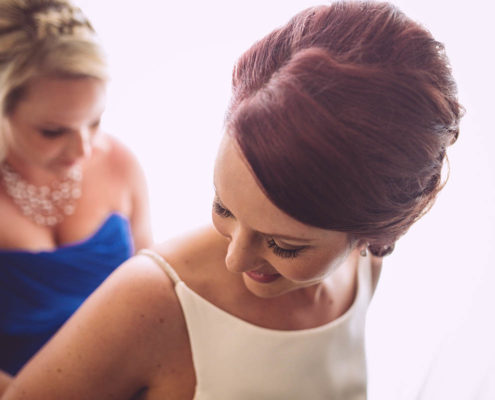 bride's maid helps bride get ready.