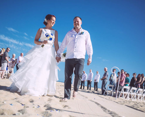 happy couple walk on beach after wedding