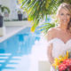 smiling bride poses with bouquet by pool