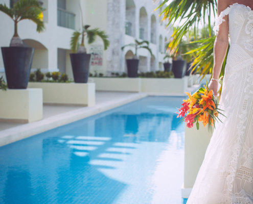 bride poses beside mexico resort swimming pool