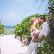 newly married couple kiss along sandy pathway