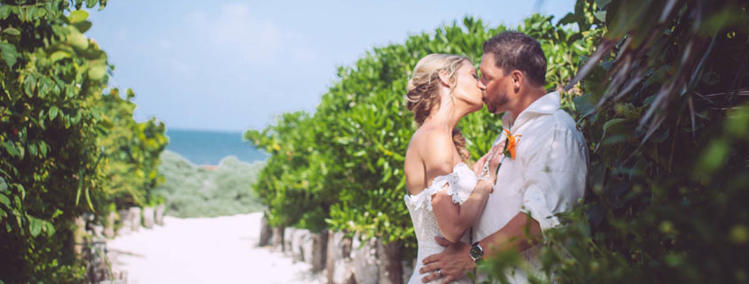 newly married couple kiss along sandy pathway