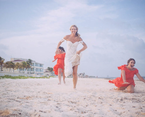 bride playfully runs along beach after wedding on white sand