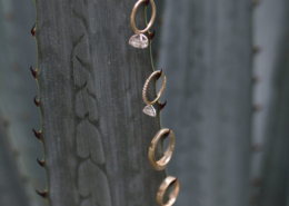 Close-up of four gold wedding rings, including two diamond engagement rings, delicately placed along the thorns of a large blue-green agave plant during a Puerto Vallarta wedding.