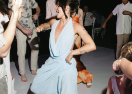 Wedding guest in a flowing light blue dress dancing barefoot with friends on an outdoor dance floor during a lively Puerto Vallarta wedding reception in Mexico.