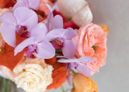 Close-up of a colorful tropical wedding bouquet featuring pink orchids, peach roses, orange flowers, and soft yellow blooms, designed for a vibrant Puerto Vallarta wedding.