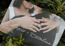 Personalized wedding invitation featuring Alexis and Catalina's engagement photo, displayed among lush tropical greenery at Dreams Bahia Mita in Mexico.